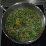 Callaloo soup simmering — creamy coconut milk with callaloo, okra, peppers, and a whole Scotch bonnet