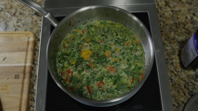 Callaloo soup simmering — creamy coconut milk with callaloo, okra, peppers, and a whole Scotch bonnet