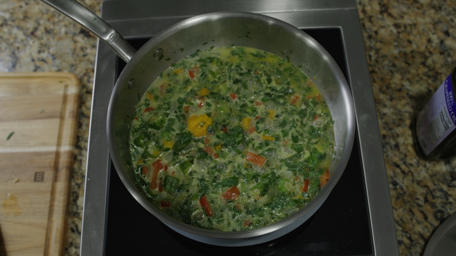 Callaloo soup simmering — creamy coconut milk with callaloo, okra, peppers, and a whole Scotch bonnet