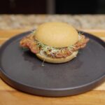 Crispy kamut oyster mushroom sandwich with alfalfa sprouts on a dark plate