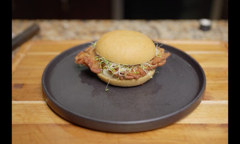 Crispy kamut oyster mushroom sandwich with alfalfa sprouts on a dark plate