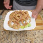 Plate of crispy kamut double-dredged red onion rings with key lime wedges