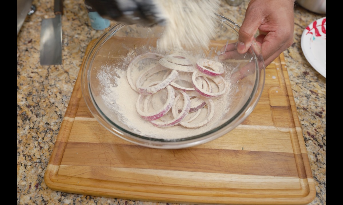 Red onion rings coated in seasoned kamut flour in a glass bowl