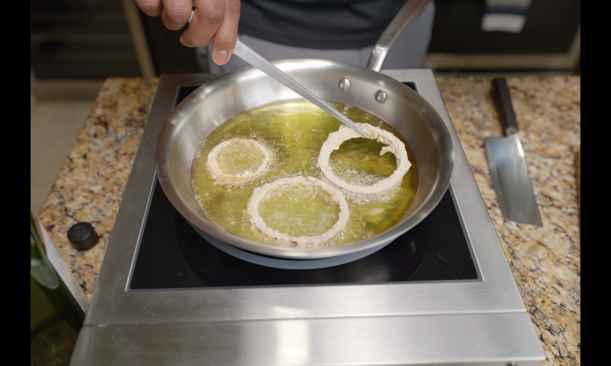 Coated onion rings frying in avocado oil
